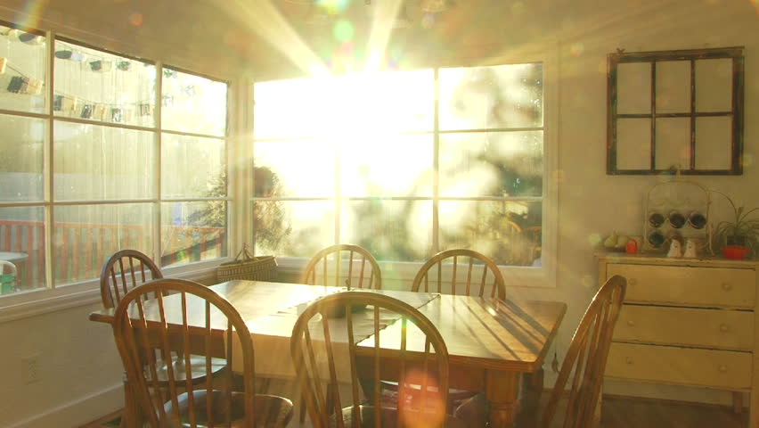 Bright sunset shines through window of dining room at house time lapse.