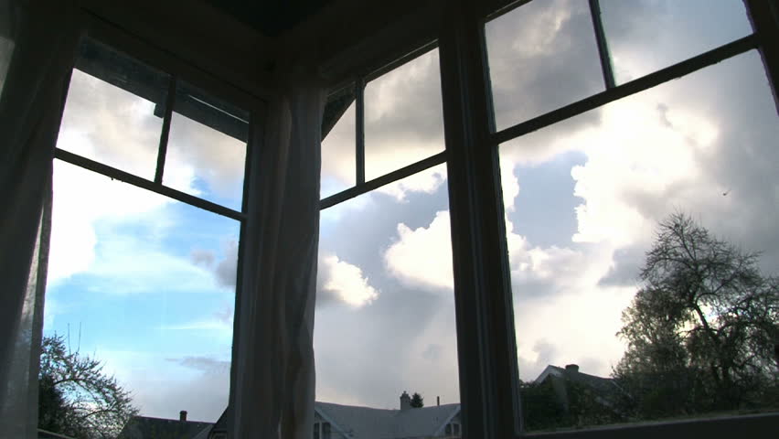 Sunsets through old windows in house. Rain clouds develop as storm rolls in.