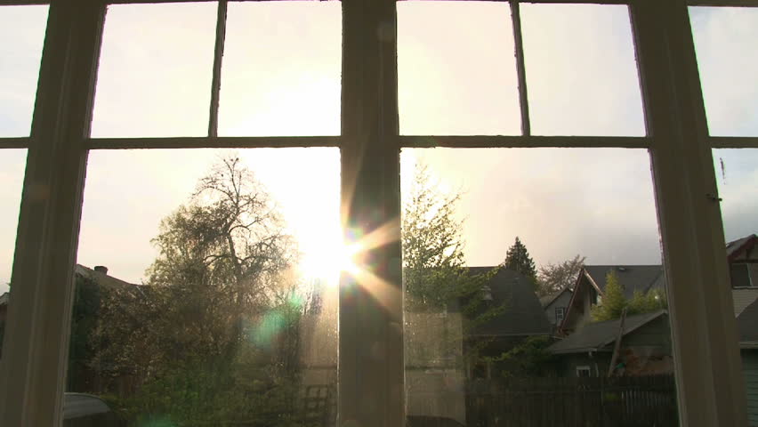 Time lapse of sunset with solar flare through house windows.