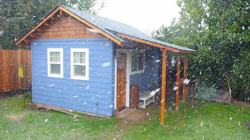 Fresh snow falling in Portland Oregon on small, blue house in winter.