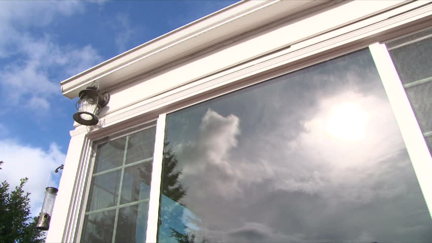Small white house time lapse with clouds passing over on sunny day as reflected