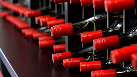 Rows of wine bottles in wine racks, close up handheld panning. 