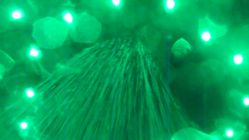Abstract visual of green liquid falling onto camera lens with lights shining