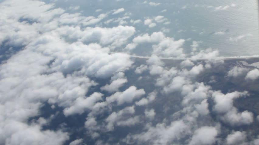 Flying in airplane over clouds and Pacific Ocean in California.