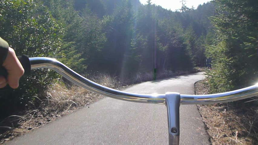 Point of View while riding bicycle through forest nature trail in Washington.