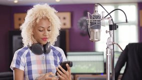 4K Female vocalist in recording studio using mobile phone for video call Dec 2016-UK