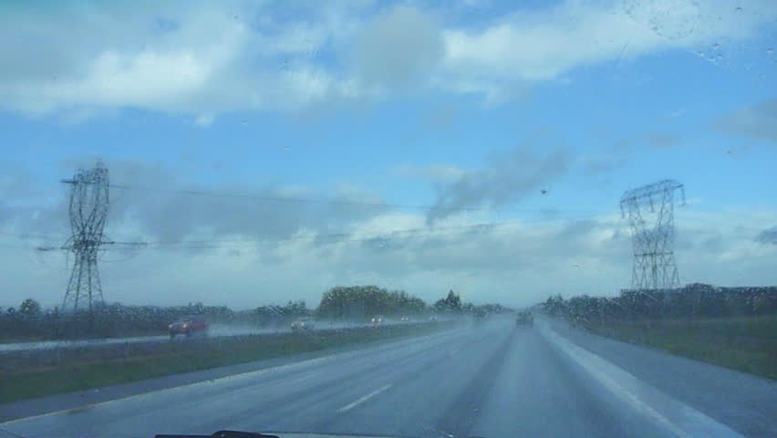 Interior car driving fast down highway during rain storm.