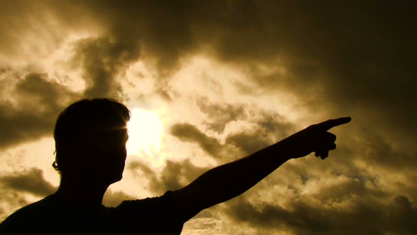 Person silhouetted raises arm and points finger in a forward direction then