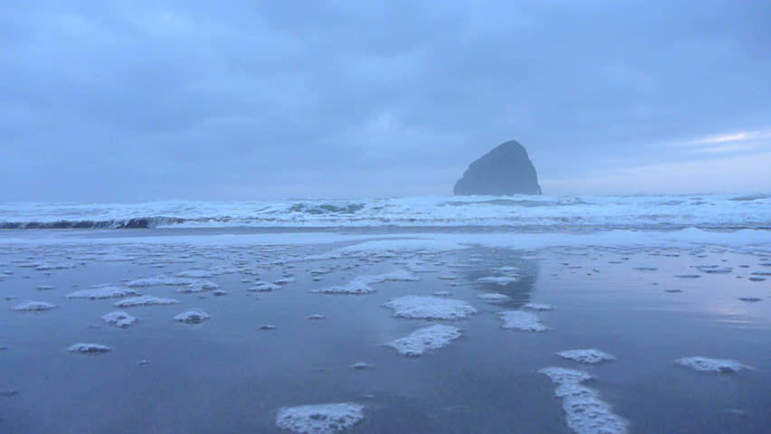 Ocean wave breaks on shoreline, reaching beyond the camera lens.