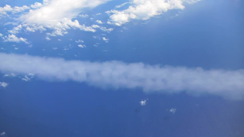 Flying in airplane over Pacific ocean and clouds showing Earth's atmosphere,