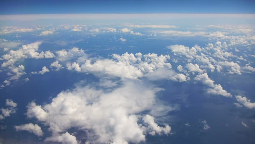 Flying in airplane over Pacific ocean and clouds showing Earth's atmosphere.