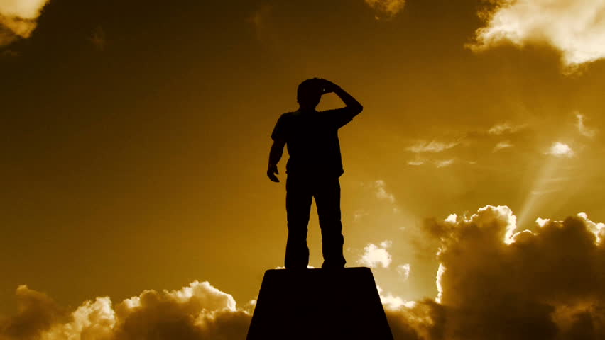 Beautiful warm cloudscape with man silhouetted standing atop pedestal structure