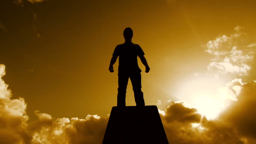 Beautiful warm cloudscape with man silhouetted standing atop pedestal structure