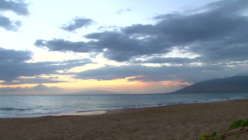 Time lapse during sunset with people walking the beach on the shores of Maui,