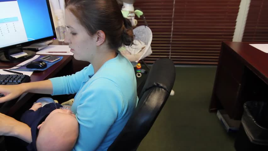 A young mother with her newborn baby working at her office