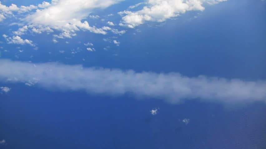Flying in airplane over Pacific ocean and clouds showing Earth's atmosphere,