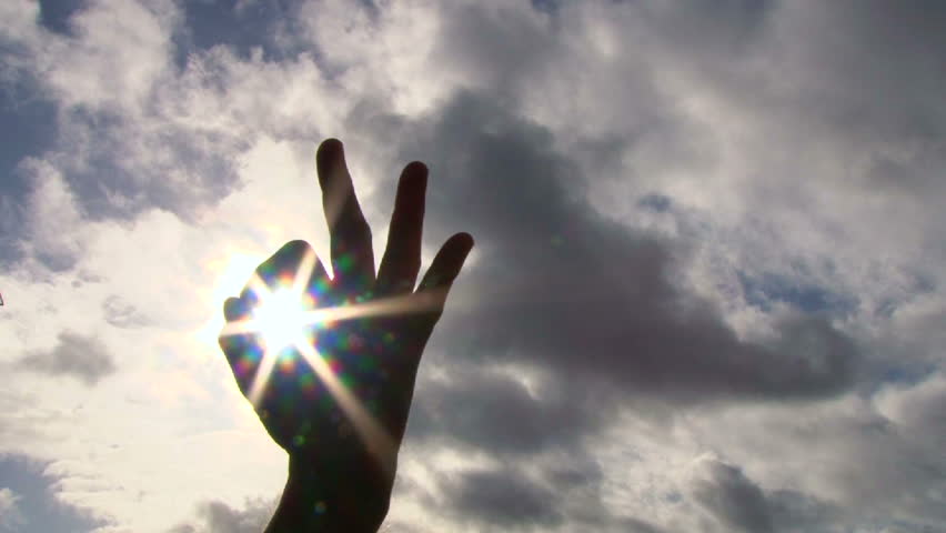 Hand rising into frame to give an a-okay sign with sun shining through, concept.
