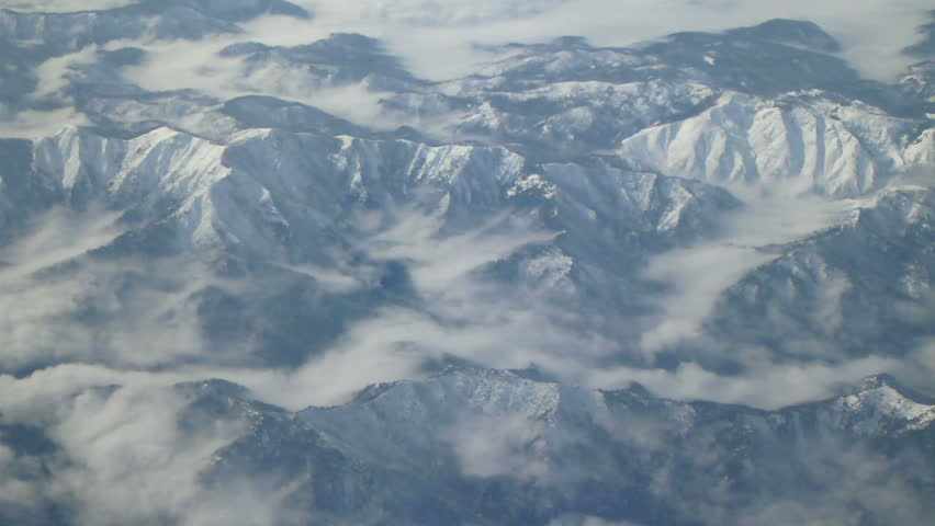 Flying in airplane over snow capped mountains in California.
