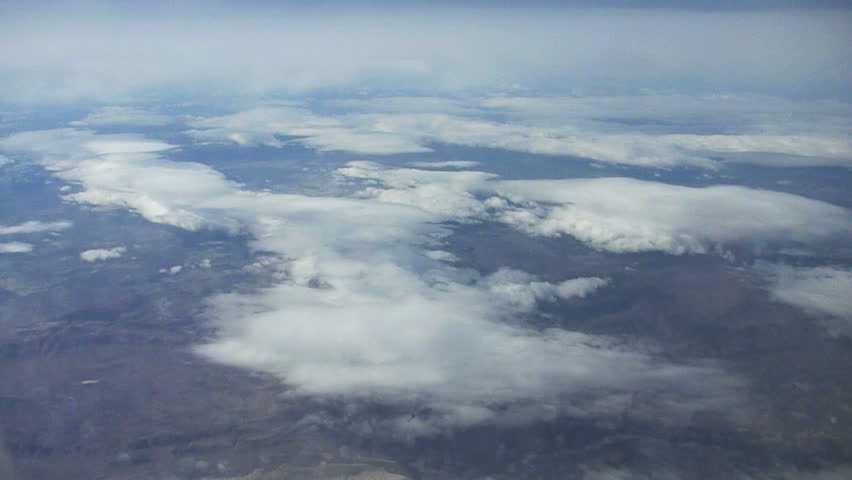 Flying in airplane through clouds over Sierra Nevada.