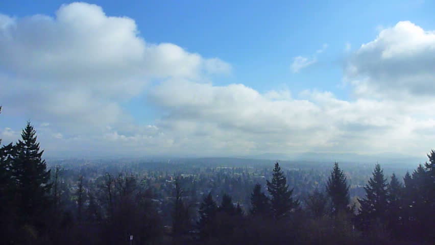 Clouds move away over urban sprawl in Portland, Oregon on blue sky day time