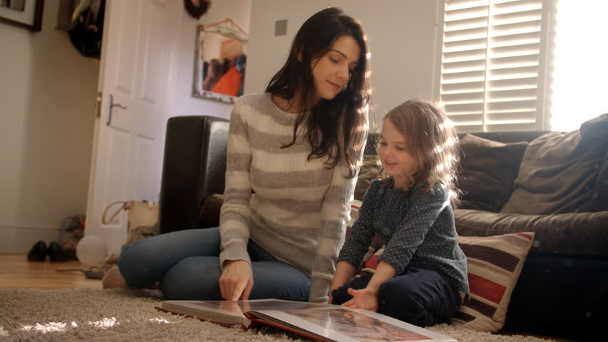 Mother And Daughter At Home Looking Through Photo Album
