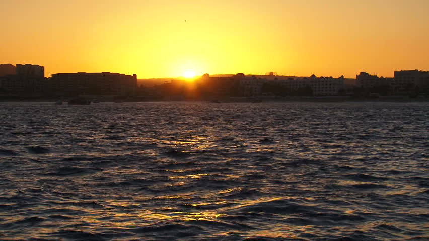Perfect sunset over Cabo San Lucas, Mexico and ocean water from cruise ship.