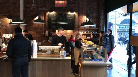 LONDON - JANUARY 12, 2017: Baristas and employees serve customers beans by weight and hot caffeinated beverages at Monmouth Coffee shop at Borough Market in London Bridge, Southwark, London, UK.
