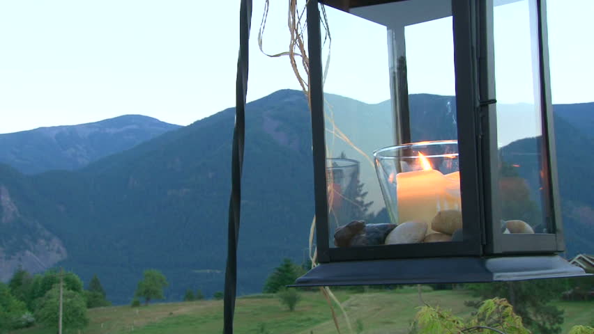 Fire burns from candle as camera pans beautiful Washington State scenery on