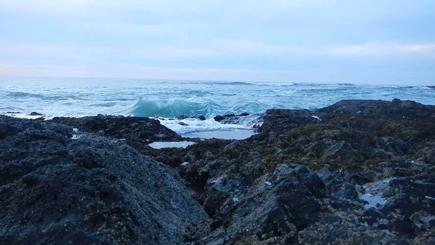Waves break over rock cliff at Pacific Ocean.