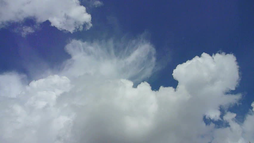 Large cumulus storm clouds build on partially blue sky day time lapse.