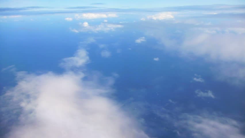 Flying in airplane over Pacific ocean dropping in altitude flying through clouds