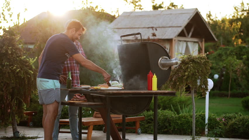 Two Caucasian males making hamburgers with fried meat and buns near barbecue grill in slowmotion | Shutterstock HD Video #23048527