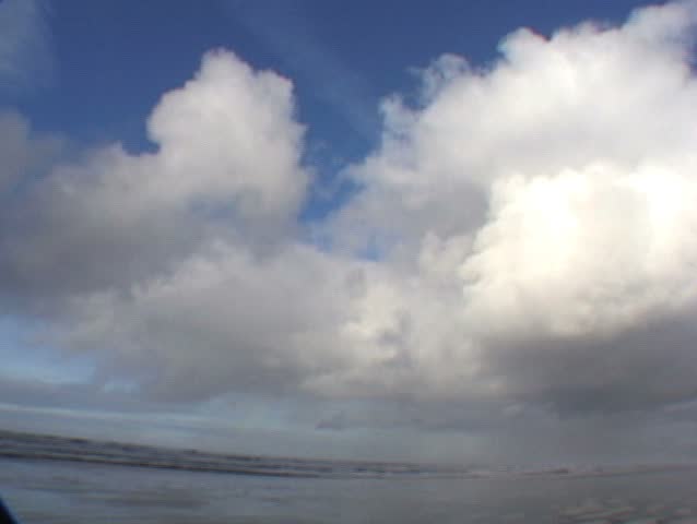 Close up clouds time lapse, pull out to wide clouds with man on beach walking by