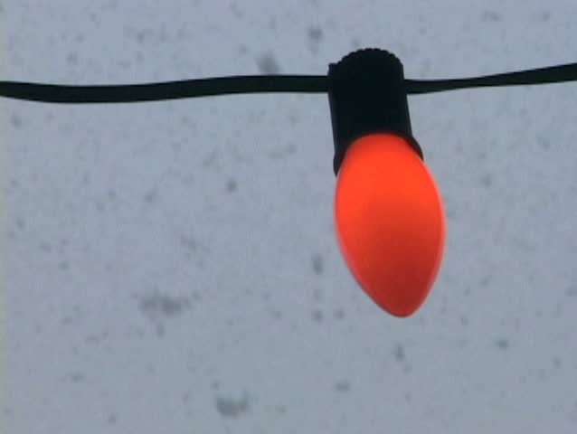 One bulb from Christmas Light string glows as snow comes down on Christmas Day