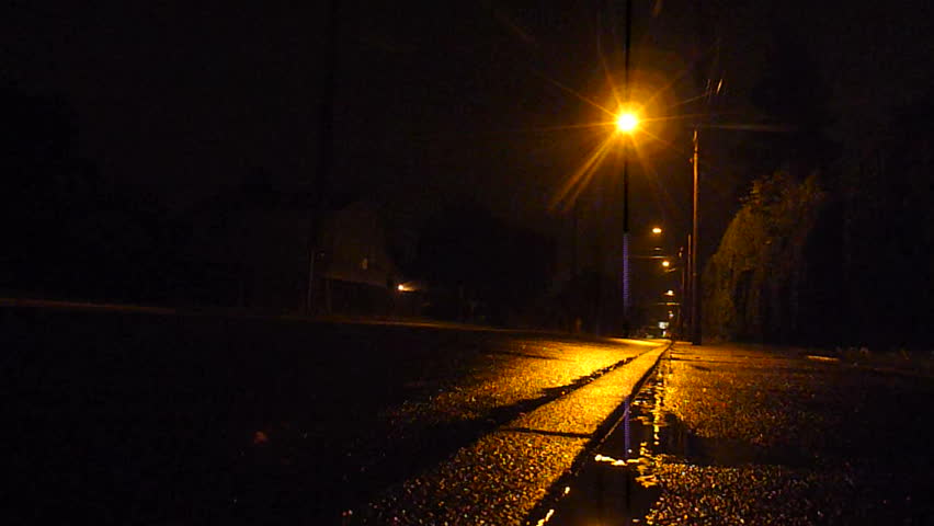 Compact car drives at night in rain storm.