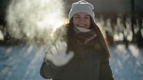 Cheery Active Woman is Throwing Snowball at the Camera Having Fun Outdoors during Winter Time. Smiling Girl Enjoying Cold Sunny Morning in the Park.
