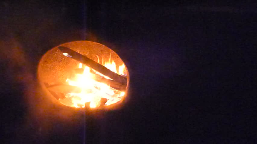 Fire burning in clay chiminea at night.