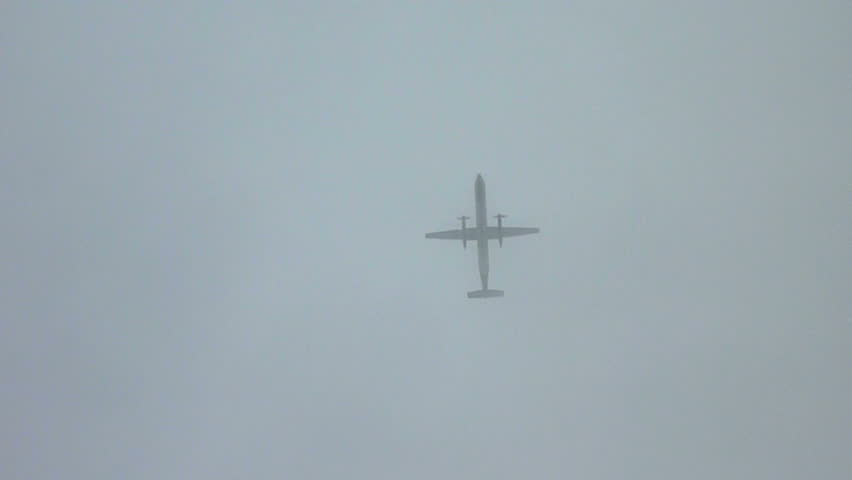 Airplane flying overhead on cloudy day.