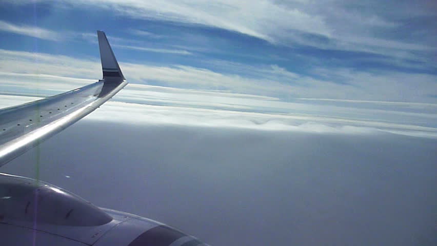 Flying high in airplane descending into clouds to land.