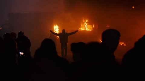 Kiev, Ukraine, January 2014: A protester walks with his hands up near the burning cars during protests against President Yanukovych in Kyiv on the street Grushevskogo January 19, 2014