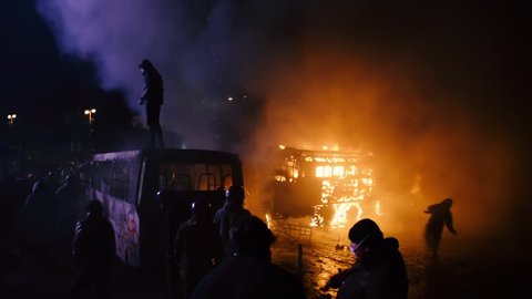 Kiev, Ukraine, January 2014: Protesters against the policy of President Yanukovych throw stones and bang next to a burnt-out machinery in clashes with police on the street Grushevskogo January 19