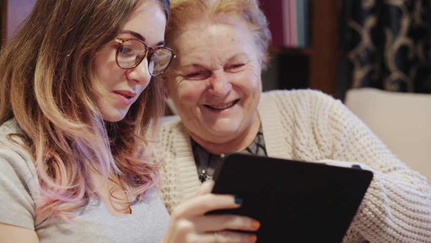 Cheerful young girl with an elderly woman playing together with digital tablet at home | Shutterstock HD Video #23073475