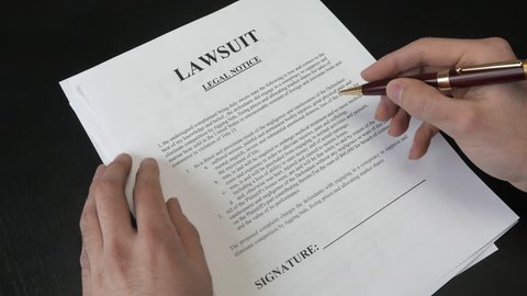 Signing a Lawsuit document. Closeup on the legal paper.