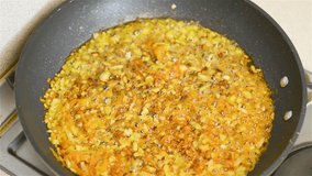 Stir frying chopped yellow onion in hot fry pan, macro slow motion