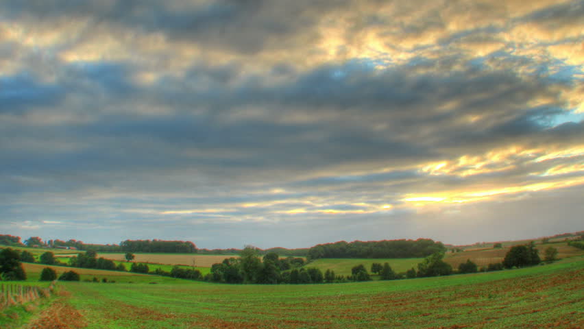 Sunset time lapse of clouds over fields, high dynamic range imaging