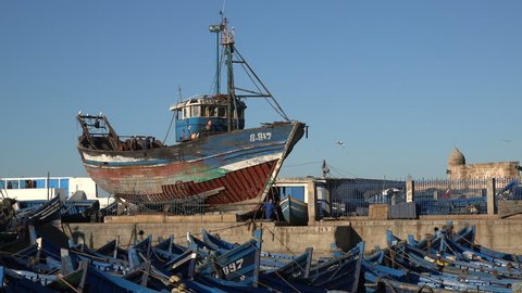ESSAOUIRA, MOROCCO - DECEMBER 2016: A wooden fishing boat is repaired in a small shipyard in the port of Essaouira in Morroco