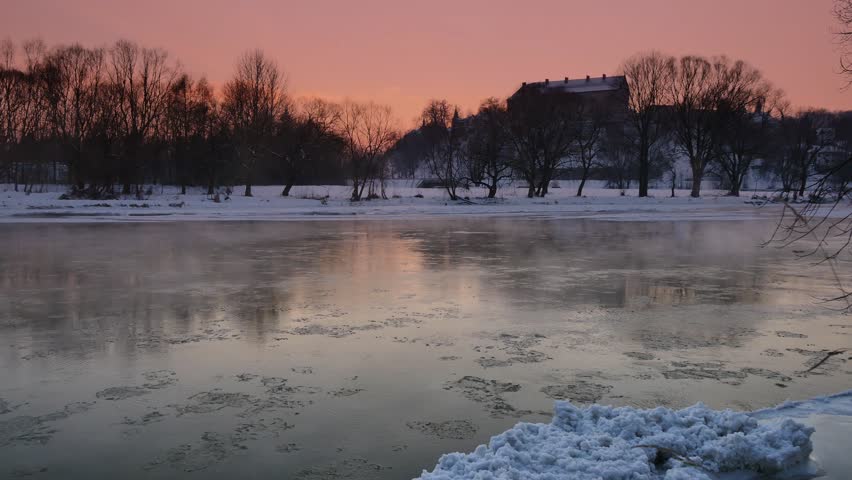 Beautiful winter sunset over cold river. Floes on the river.
