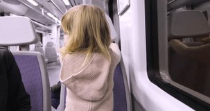 4k video. Three years old blonde child talking to woman mother sitting backwards in a train inside a tunnel or by night
