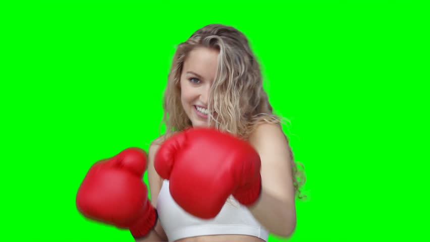 A woman punching forward at the camera while in front of a green background