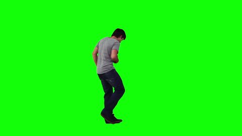 A man is dancing on his own against a green background